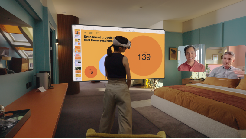 Una persona usando un Apple&nbsp;Vision&nbsp;Pro y teniendo una llamada de FaceTime. Los recuadros de las otras personas de la llamada se muestran junto a una pantalla compartida.