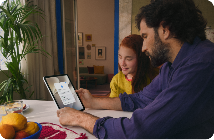 Un padre e la figlia adolescente che guardano insieme lo schermo di un iPad.