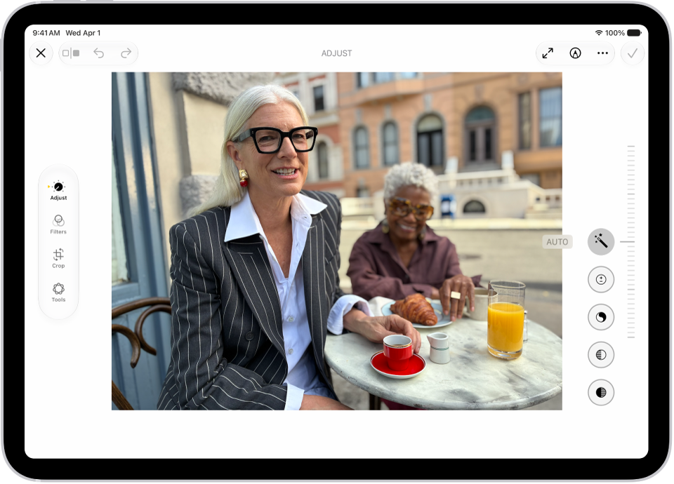 The Edit screen of the Photos app showing a photo in the center. To the left of the photo are the Style, Adjust, Crop, and Clean Up buttons; Adjust is selected. To the right of the photo are buttons for editing effects and a slider to adjust each effect level.
