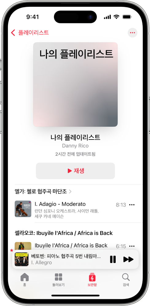 iPhone이 Apple Music Classical에서 개인 플레이리스트를 표시함. 화면 상단에는 앨범 표지, 플레이리스트 이름 및 재생 버튼이 있음. 화면 하단 부근에는 미니 플레이어가 있고, 현재 재생 중인 트랙을 표시함. 미니 플레이어 아래에는 홈, 둘러보기, 보관함 및 검색 버튼이 있음.