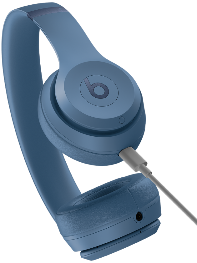 Ein USB-C-Kabel, das mit dem Ladeanschluss der rechten Ohrmuschel der Beats&nbsp;Solo&nbsp;4 (unter der Systemtaste) verbunden ist.