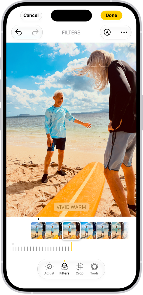 On iPhone, a photo is being edited in the Photos app. The Filters button is selected, and the Vivid Warm filter is selected. A slider is available below the filter options to adjust the intensity of the filter. The Cancel button is in thetop-left corner of the screen and the Done button is in the top-right corner.