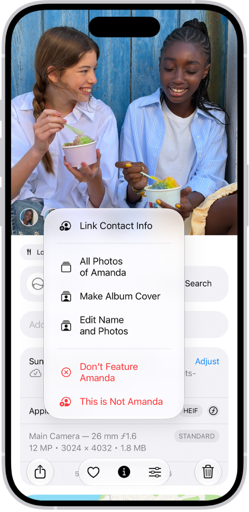 The top half of the iPhone screen shows a photo open in the Photos app. In the bottom-left corner of the photo are the faces of the people that appear in the photo. One of the faces has a question mark next to it. A menu of options includes, from top to bottom, All Photos, Make Key Photo, Edit Name and Photos, and Don’t Feature This Person.