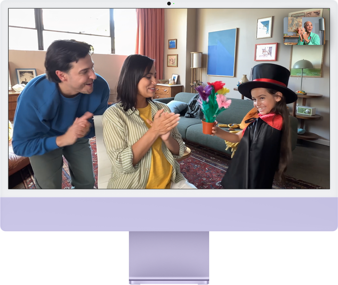 An iMac showing a video call with Center stage keeping three people in frame. 