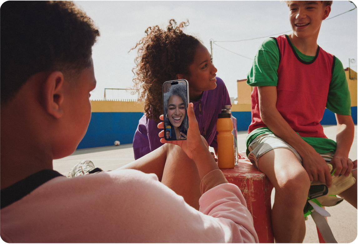 Un adolescente, insieme a un gruppo di amici, che sta effettuando una chiamata FaceTime video su iPhone.